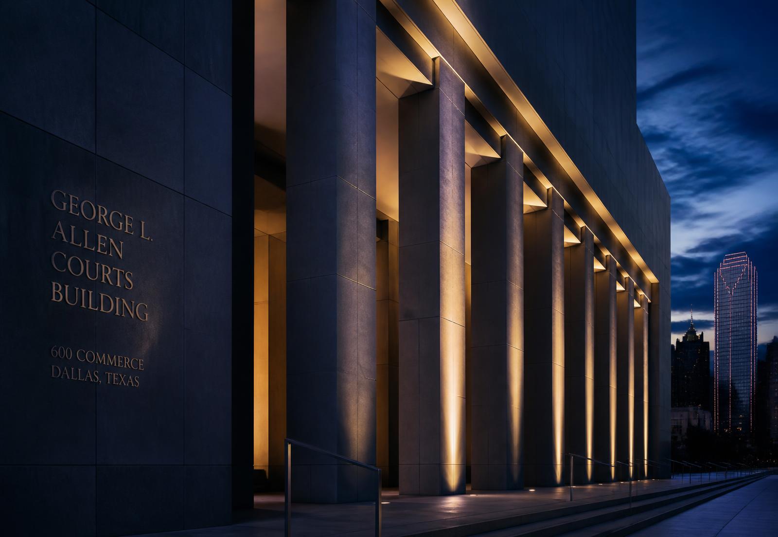 Illuminated stone colonnade of a courthouse at dusk in Dallas